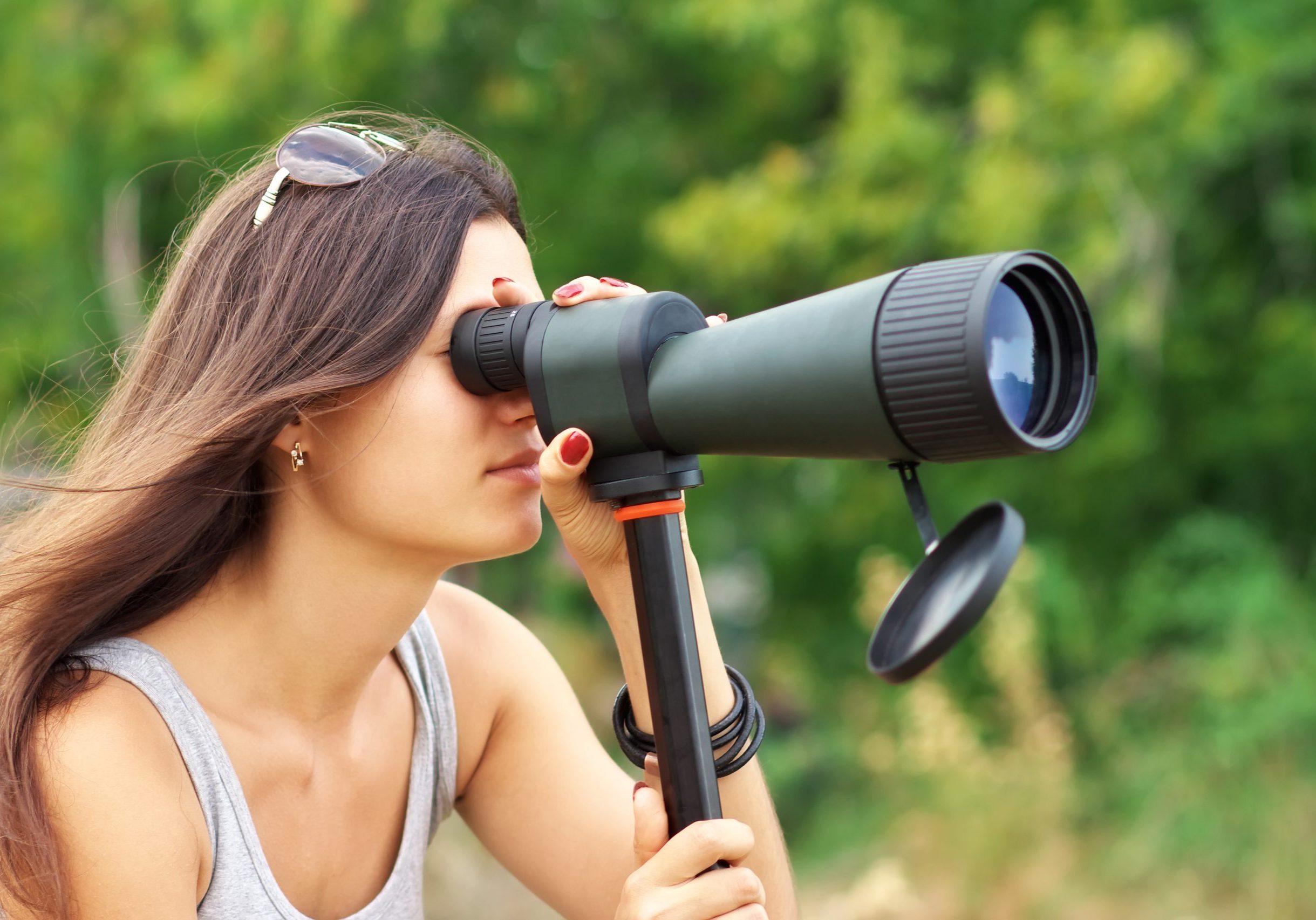 Positive girl who is watching in spotting scope.